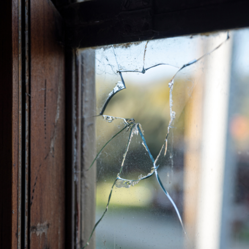 Broken window glass with cracked and shattered pane requiring professional glass replacement.
